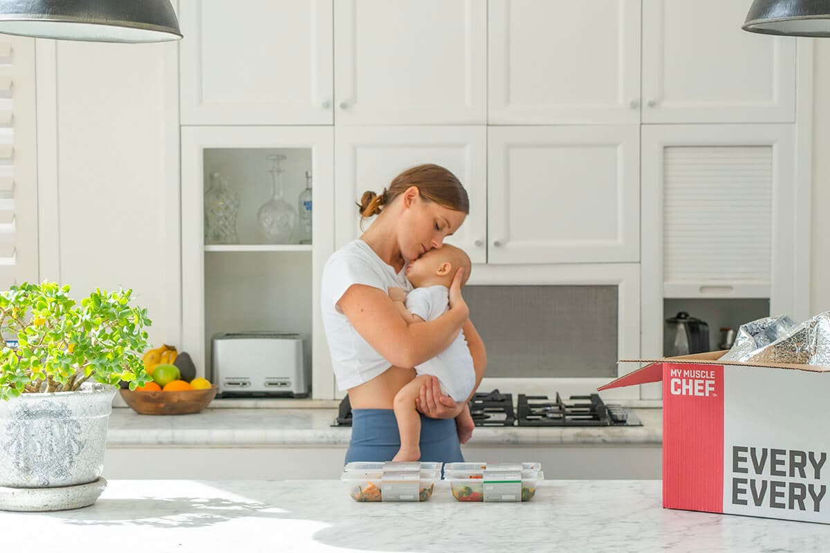 Mum with baby and my muscle chef meals on bench