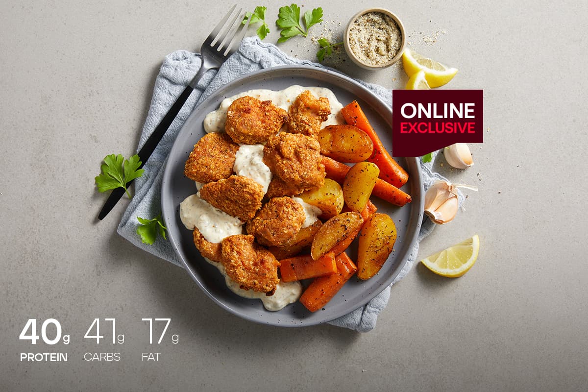 My Muscle Chef Crumbed Chicken With Roasted Vegetables & Lemon Herb Sauce plated on a table