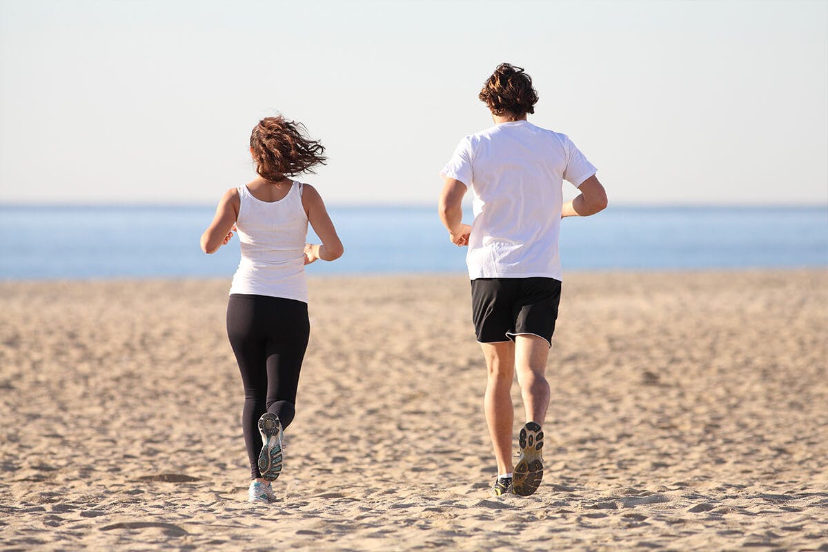 Male and female running at the beach